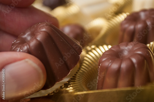 Closeup of hand of man taking a Chocolate in shaped kouglofs in golden box collection