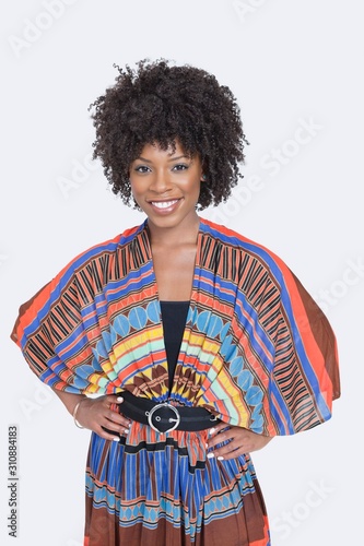 Portrait of beautiful African American woman in traditional wear standing over gray background
