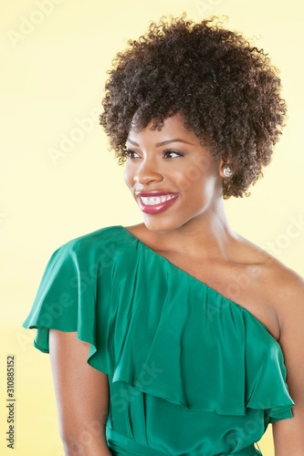 Beautiful African American in an off shoulder dress looking away over colored background