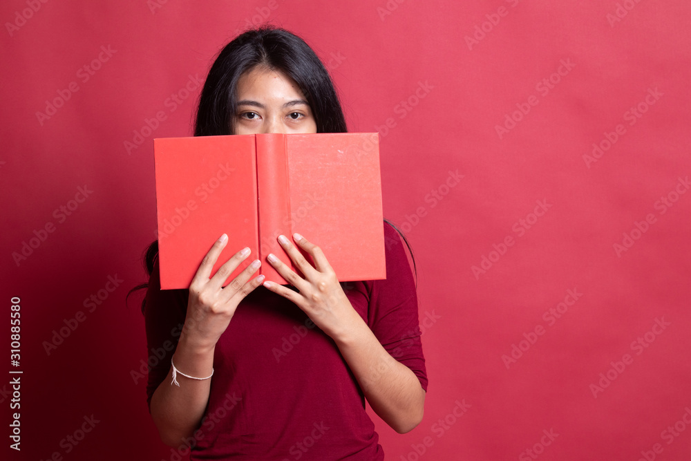 Young Asian woman with a book cover her face. Young Asian woman with a book cover her face.