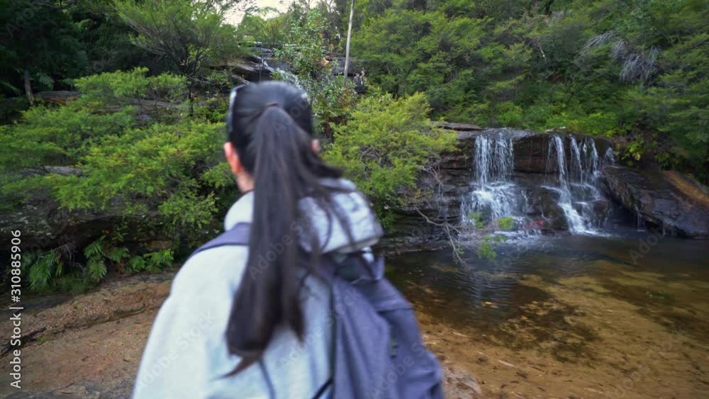 Hiking woman walks straight past a small waterfall in the Blue Mountains National Park Hiking woman walks straight past a small waterfall in the Blue Mountains National Park