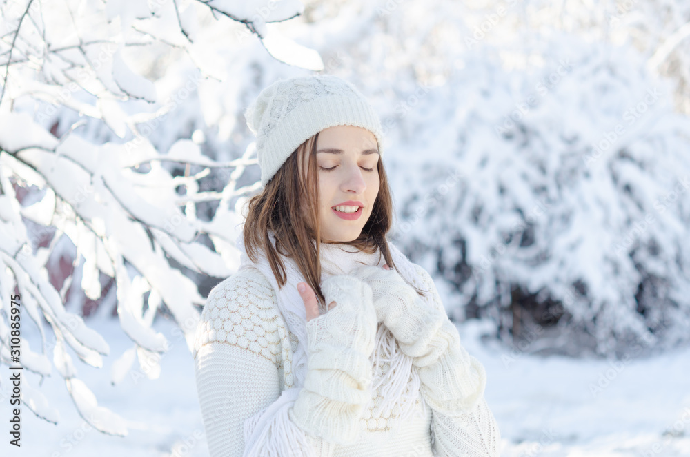 Portrait of young beautiful woman in white warm sweater and hat enjoying the winter time. Portrait of young beautiful woman in white warm sweater and hat enjoying the winter time.