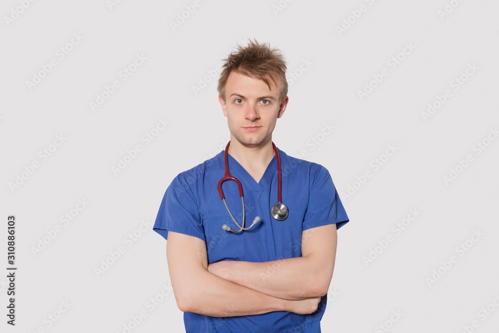 Portrait of a serious male surgeon standing with arms crossed over gray background Portrait of a serious male surgeon standing with arms crossed over gray background
