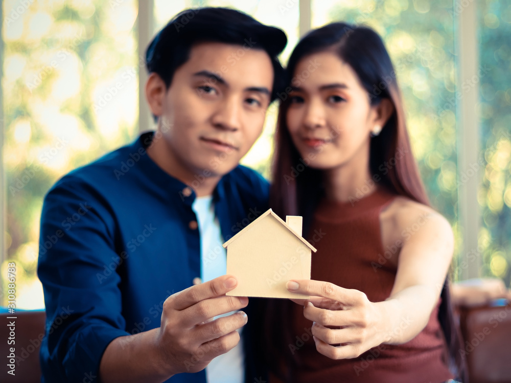 young Asian couple holding model house , selective focus on model house. young Asian couple holding model house , selective focus on model house.