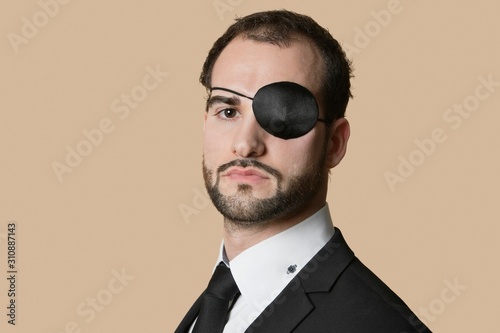 Obraz na plátne Portrait of a young businessman with eye patch over colored background