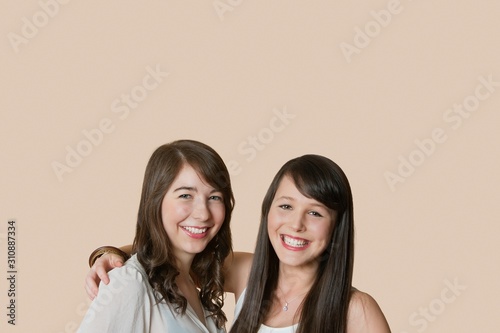 Portrait of young female friends over colored background