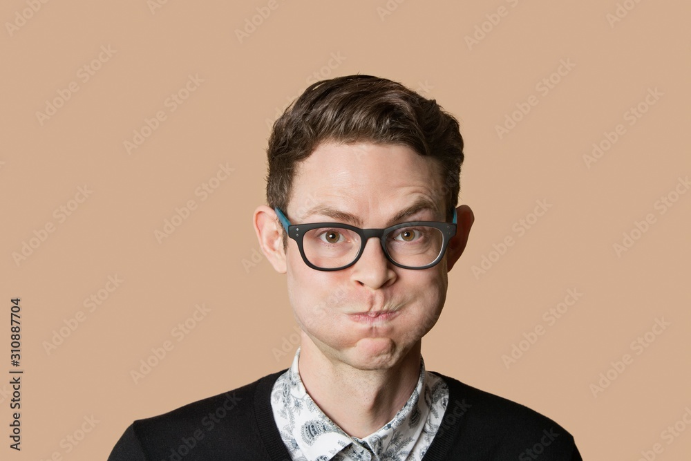 Portrait of mid adult man puffing cheeks over colored background