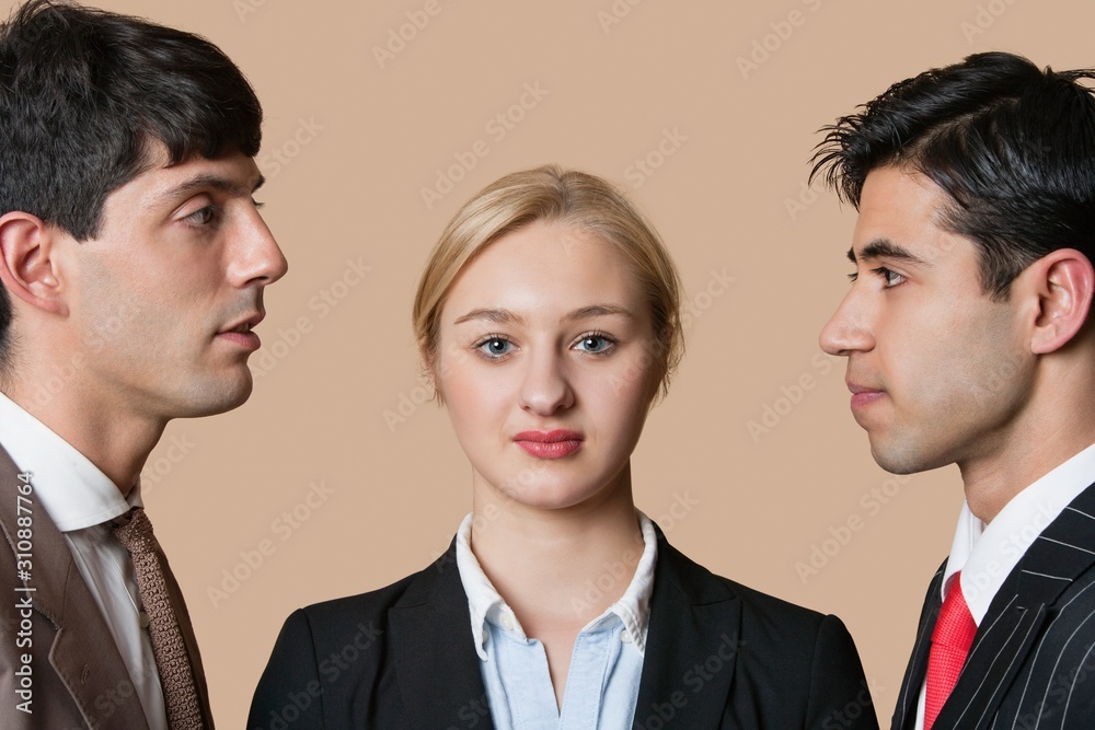 Portrait of a young businesswoman with male colleagues staring at each other over colored background Portrait of a young businesswoman with male colleagues staring at each other over colored background
