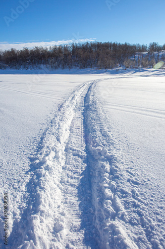 Trail from a snowmobile on a frozen and snowy river bed.