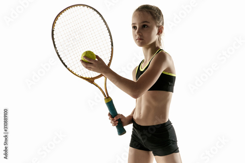 Little caucasian girl playing tennis on white studio background. Cute model posing confident and calm in motion, action. Youth, flexibility, power and energy. Ad, sport, healthy lifestyle concept. © master1305