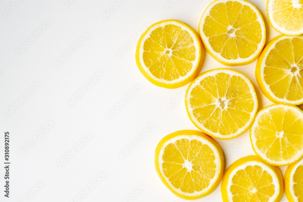 Lemon slices randomly lie on one side on a light table surface. Flat lay, close-up. Lemon slices randomly lie on one side on a light table surface. Flat lay, close-up.