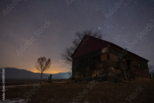 Beautiful night landscape. Small christian church at the night. A colorful star in the sky with an orientation to the northern star. 