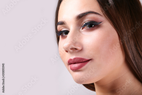 Portrait of young beautiful woman with perfectly clean face skin wearing professional make up. Female with long black hair. Close up, copy space background.