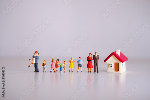 Miniature people, big family standing with mini house using as family concept