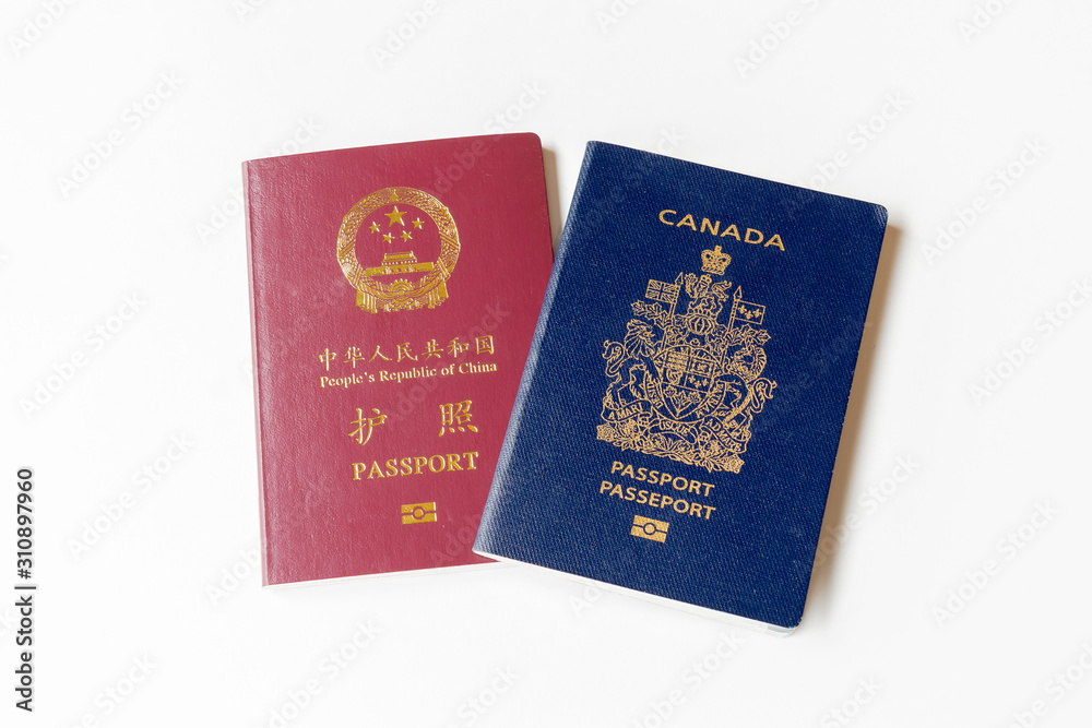 One Canadian passport and one Chinese passport on white background. One Canadian passport and one Chinese passport on white background.