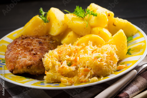 Minced pork cutlet served with potatoes and sauerkraut salad. photo