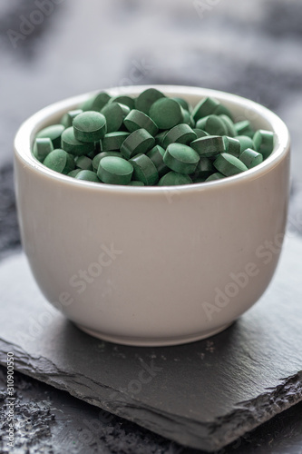 grüne Spirulina als Nahrungsergänzungsmittel auf grauem Grund