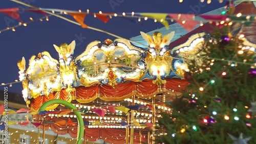 Beautiful illuminated merry-go-round details while rounding at Christmas fair in slow motion. Vintage colorful carousel with angel on the top