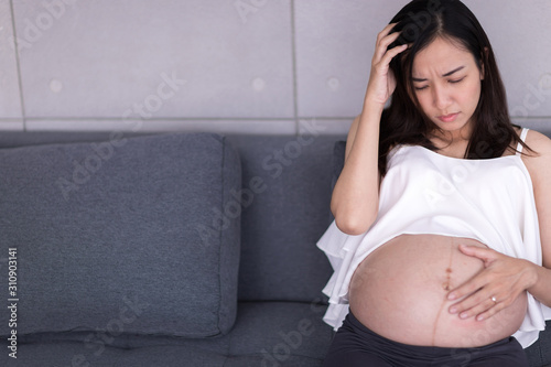 A pregnant woman sits as anxious about the child in her womb.
