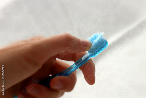 Fototapeta Used old toothbrush with a frayed bristles in hand on light background