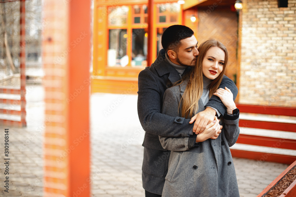 Loving couple in a coat walk along the street