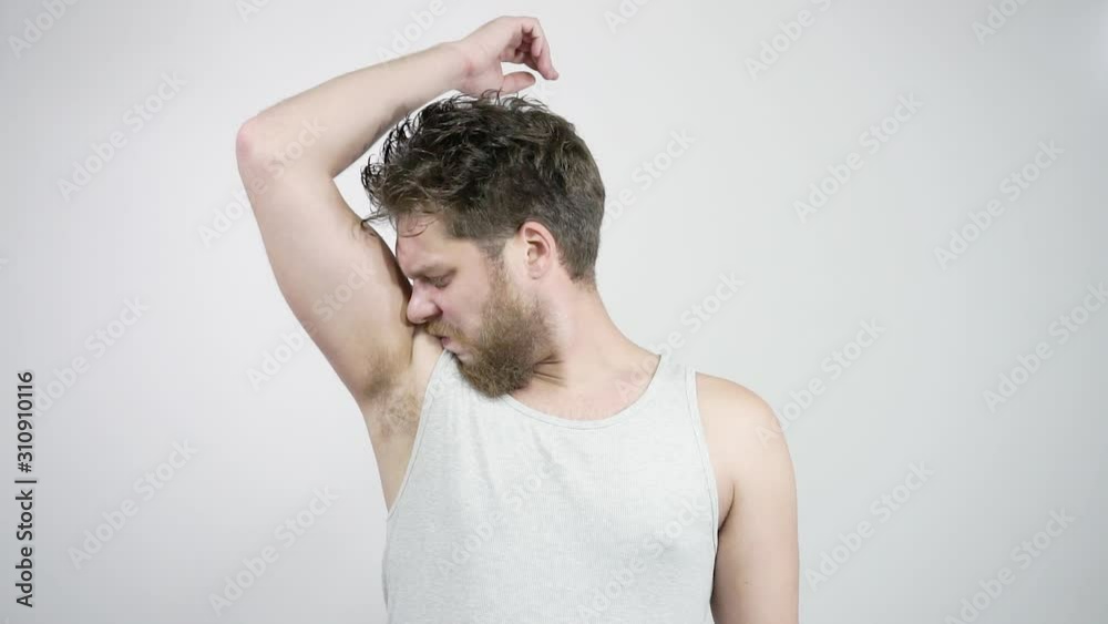 The young man feels an unpleasant smell from the armpits and is disgusted The young man feels an unpleasant smell from the armpits and is disgusted