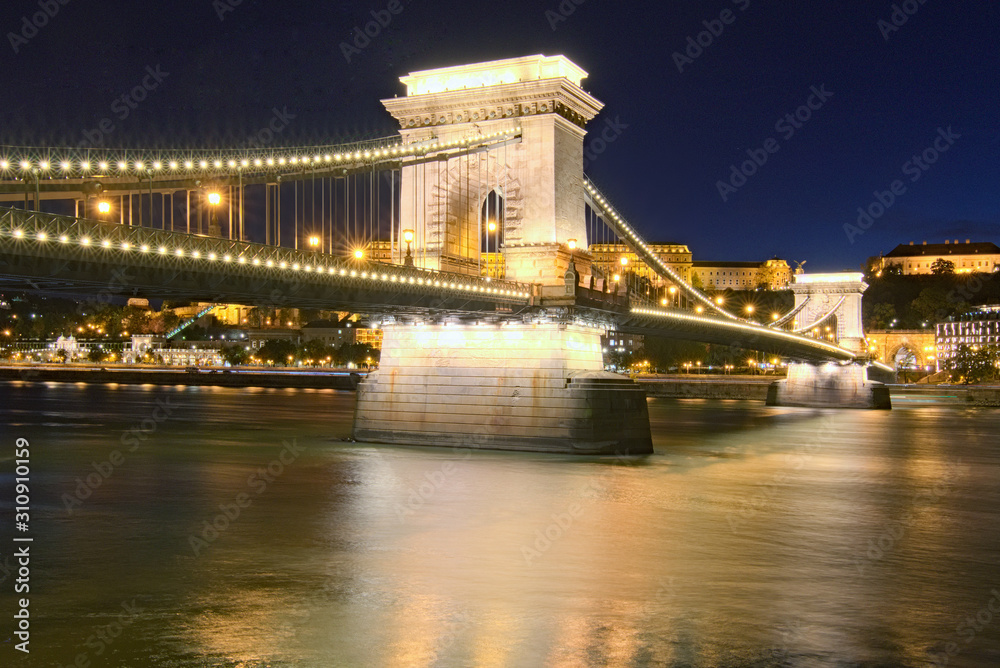 Scenic evening landscape view of ancient Chain Bridge. Illumination of the city. Famous touristic place and travel destination in Europe. Budapest, Hungary