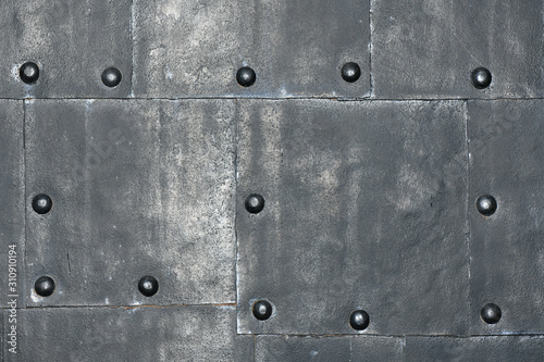 Metal wall with rivets. Faded shiny
