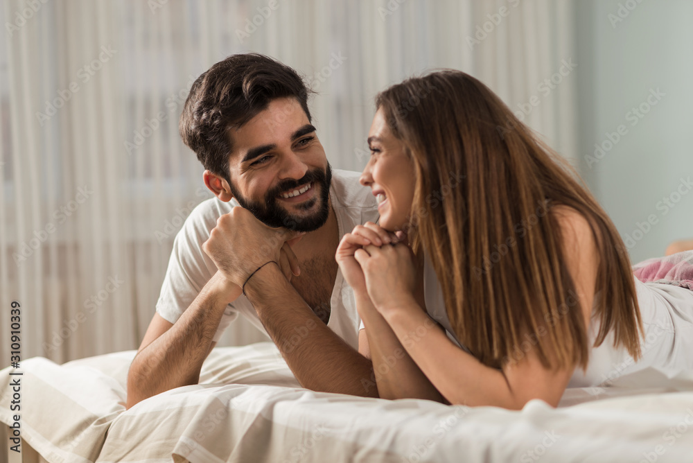 Young loving couple relaxing together on a bed and talking to each other Young loving couple relaxing together on a bed and talking to each other