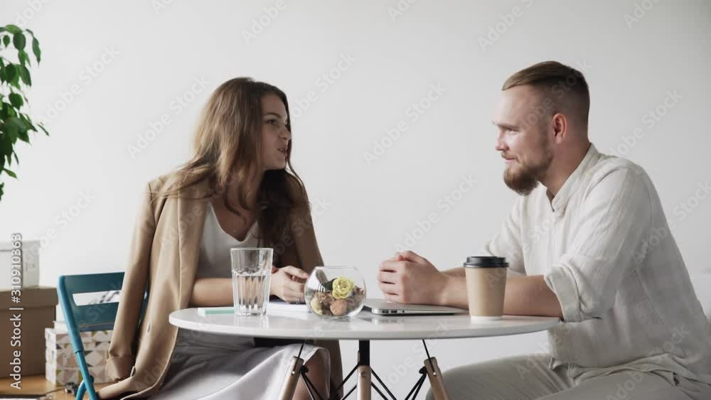Couple of happy colleagues talking and flirting while sitting in dining room in office during coffee break Couple of happy colleagues talking and flirting while sitting in dining room in office during coffee break