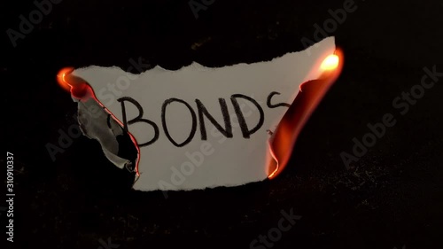 Bonds word written on white paper burns. Fire with smoke and ashes on black background photo