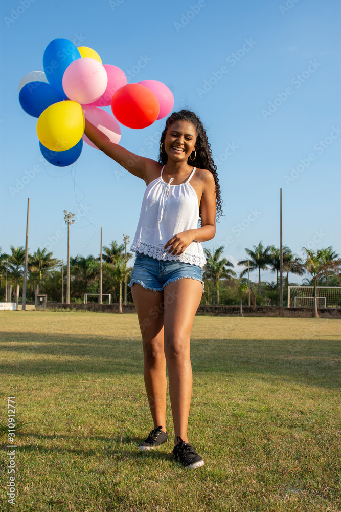 pretty young woman holding colorful balloons in relaxed moment