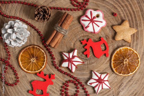 Christmas and New Year pattern from ginger cookies, slices of orange, cinnamon, pine cones, red beads and deers on a wooden background. Christmas, winter, new year concept. Flat lay, top view