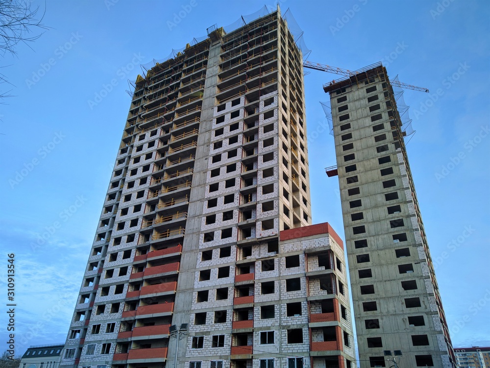 Fototapeta premium Construction of a multi-storey monolithic house of gray concrete against the blue sky