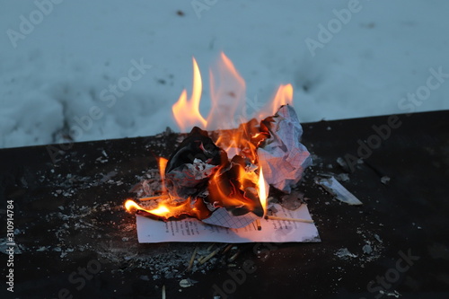 Atmosphere fire in winter outdoors. Burning paper in the snow