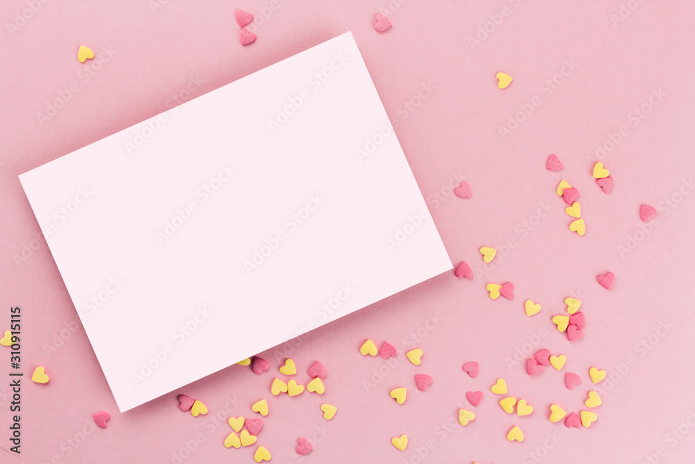 card on a background of heart-shaped confectionery confetti on a pink background copy space. Yellow and pink hearts.