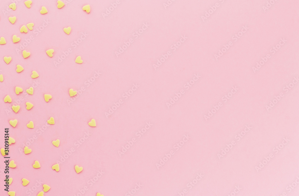  yellow confetti in the shape of hearts on a pink background copy space.