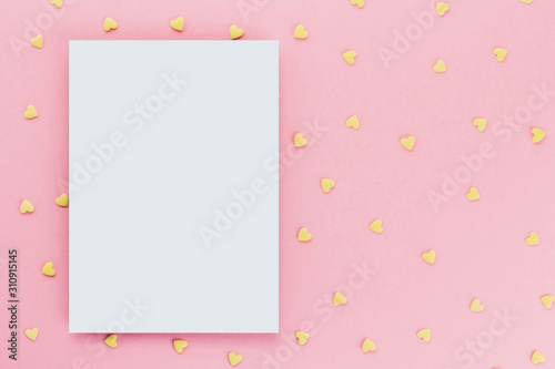 card on a background of heart-shaped confectionery confetti on a pink background copy space. Yellow hearts.