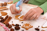 Young hands decorate gingerbread cookies with white icing - close up