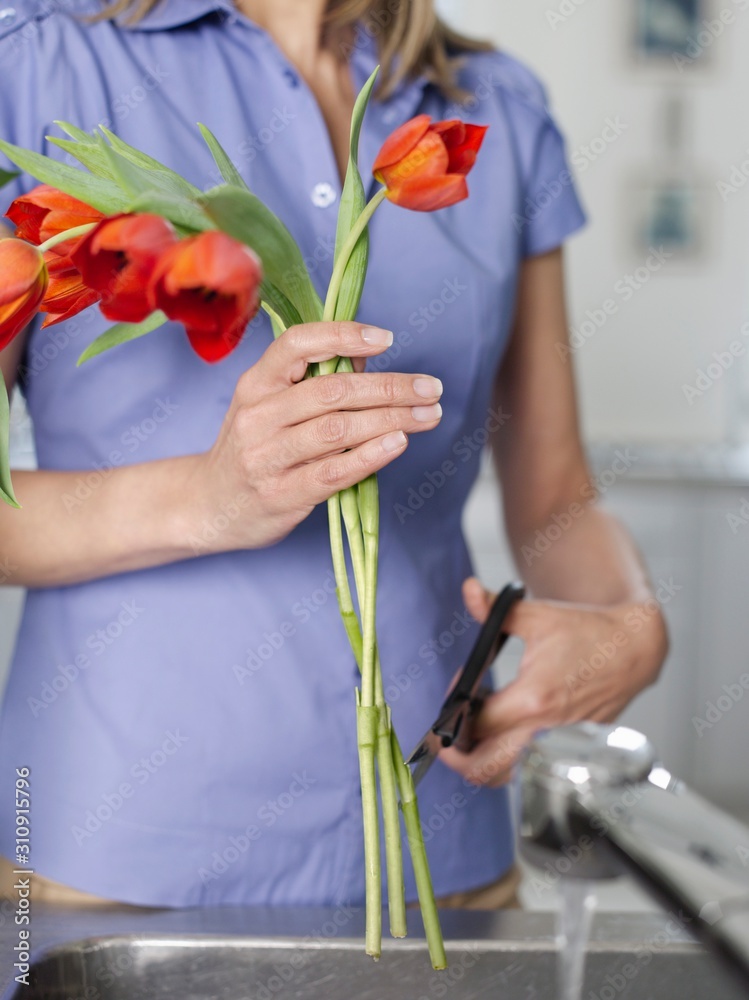Midsection Of Woman Cutting Flowers In Kitchen Sink