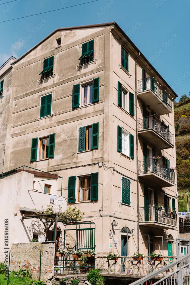 Open balconies and wooden window shutters. Residential old house in Italy with balconies. Large multi-storey grey house