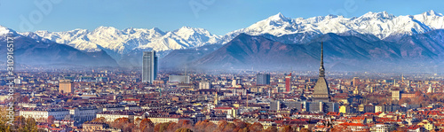 Aerial panoramic winter view on Turin city center with Mole Antonelliana, modern skyscrapers and other buildings, clear blue sky morning with Alps full of snow on background