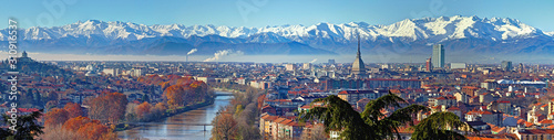 Aerial panoramic winter view on Turin city center with Mole Antonelliana, modern skyscrapers and other buildings, clear blue sky morning with Alps full of snow on background © Marco