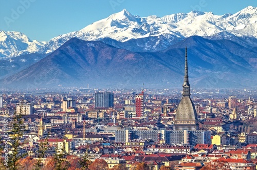 Aerial panoramic winter view on Turin city center with Mole Antonelliana, modern skyscrapers and other buildings, clear blue sky morning with Alps full of snow on background