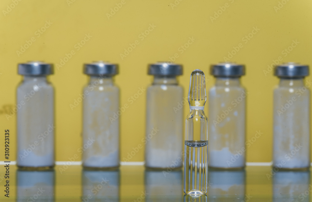 Glass medical ampoule vial for injection. Medicine is liquid sodium chloride with of aqueous solution in ampulla. Close up. Bottles ampule multicolor on background color and water. Human plasma. Glass medical ampoule vial for injection. Medicine is liquid sodium chloride with of aqueous solution in ampulla. Close up. Bottles ampule multicolor on background color and water. Human plasma.