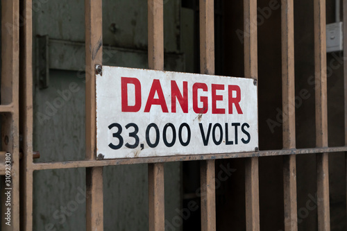 Electricity safety danger sign on a locked metal gate photo