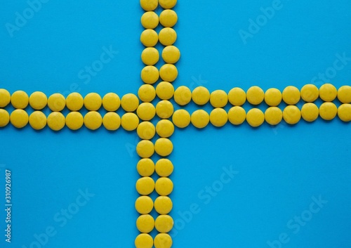 The swedish flag made of yellow candy on blue solid background