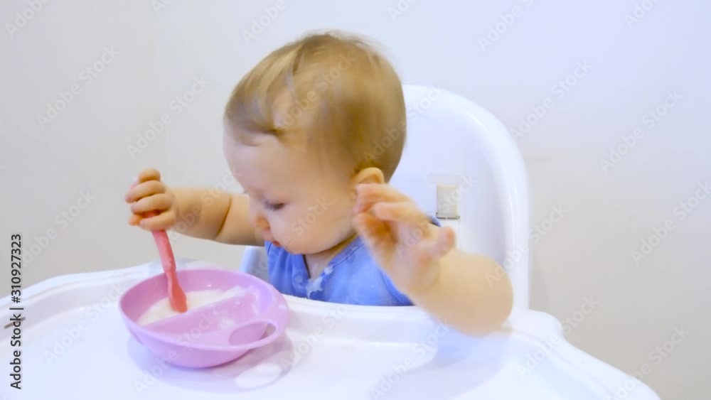 A child for the first time in his life eats porridge himself. The child eats for the first time on his own A child for the first time in his life eats porridge himself. The child eats for the first time on his own