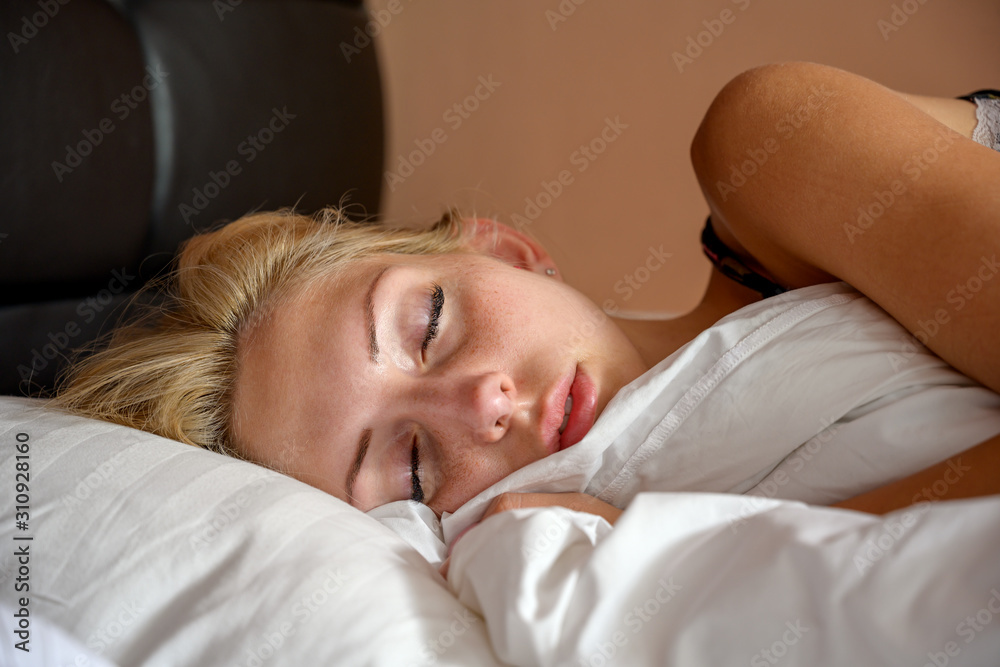 Close up photo of an attractive young woman sleeping in bed