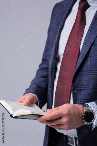 businessman in a jacket holds a diary in his hands and plans the next day with a clock on his hand